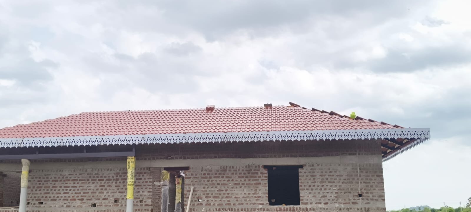 Brick house with red shingle roof and decorative white fascia