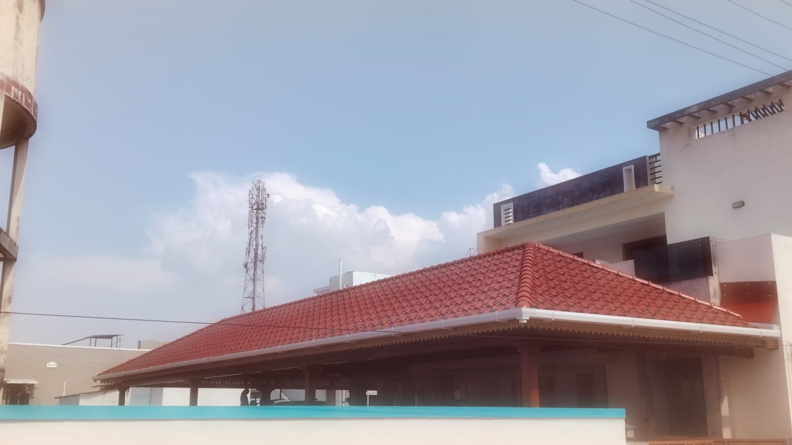 Large open-air pandal roof with red tiles and white gutters