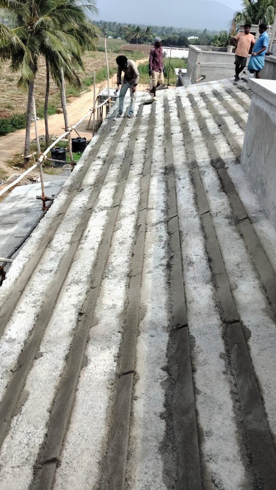 Workers finishing cement base on a large sloped roof