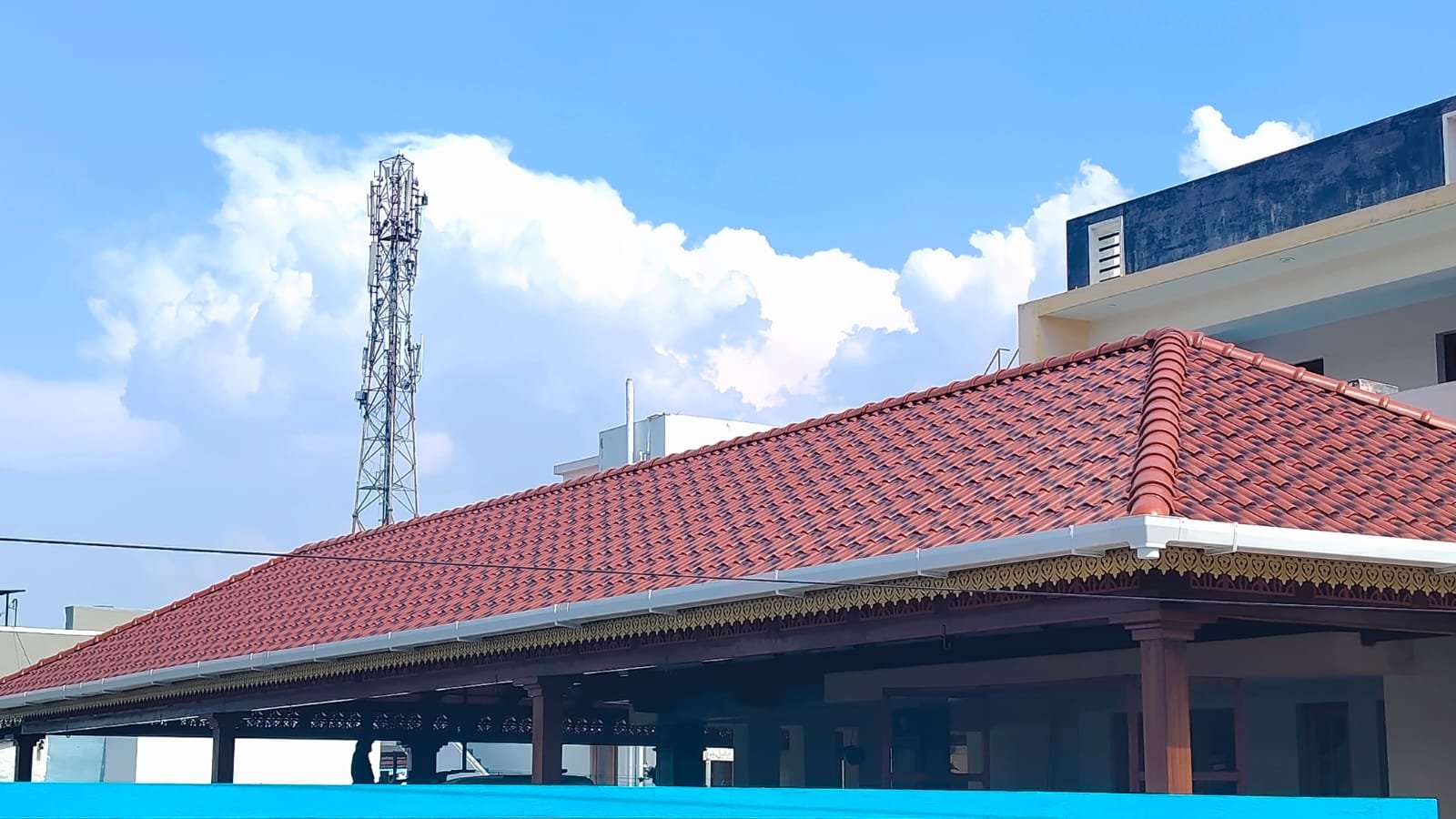 Community pandal with red tiles, white gutters and yellow valance